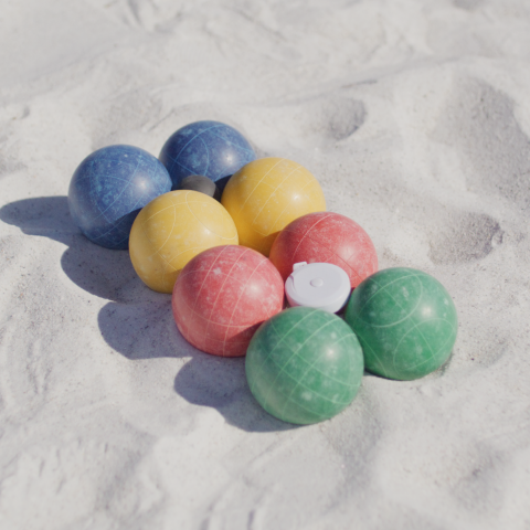 Colorful bocce balls arranged on sandy surface.
